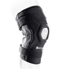 Ceļa ortoze Compex Bionic – melna elpojoša ceļgala saite ar sešstūra patellas atvērumu, silikona joslām un atstarojošu lenti; attēls uz balta fona.